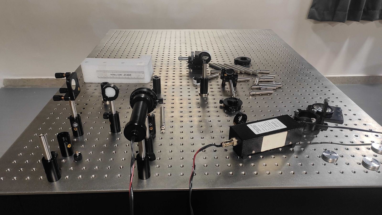 Optical table in the Delta Q lab with mirrors, mounts and an acousto-optic modulator